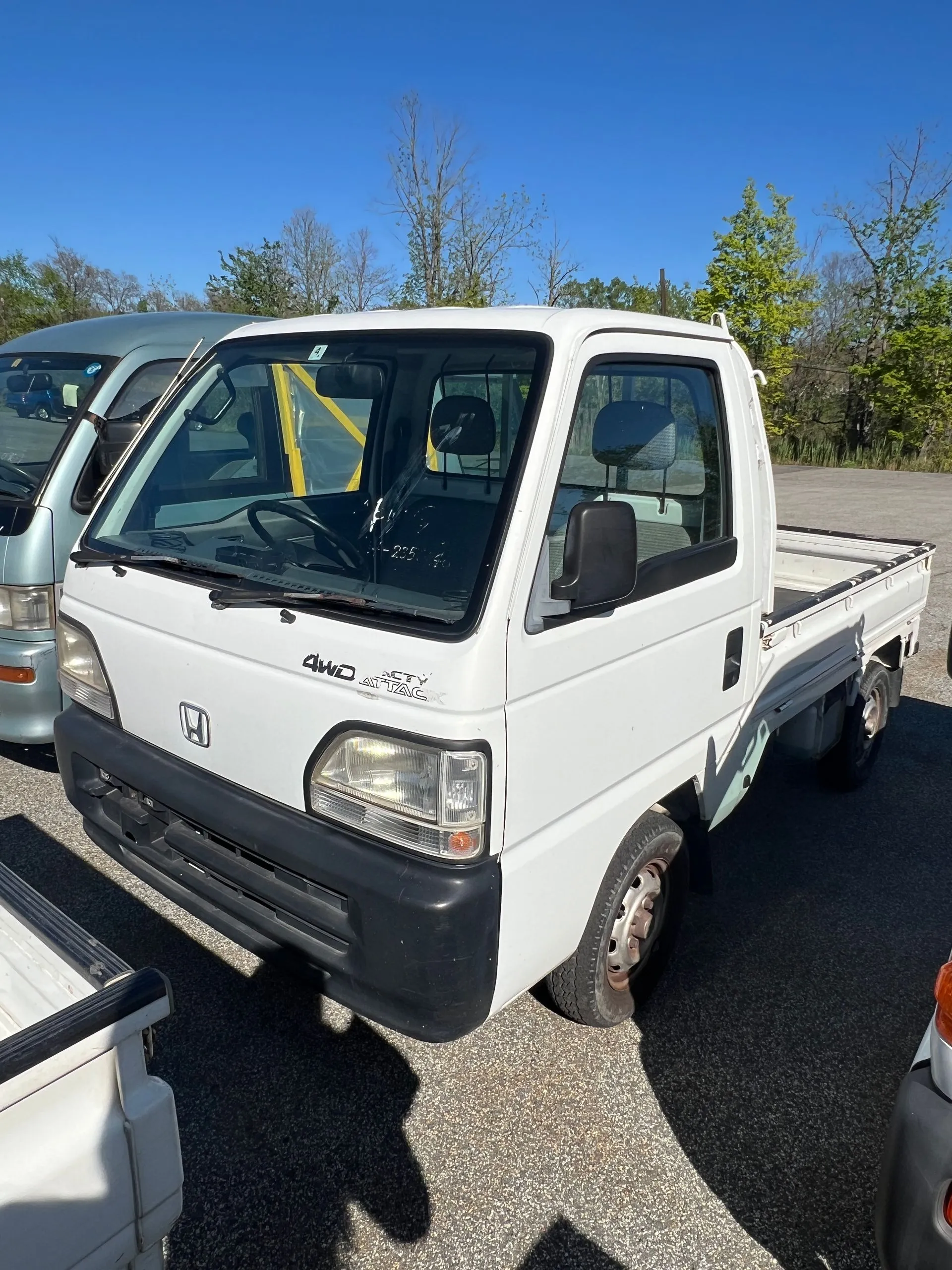 White Honda Acty kei truck viewed from the front and side