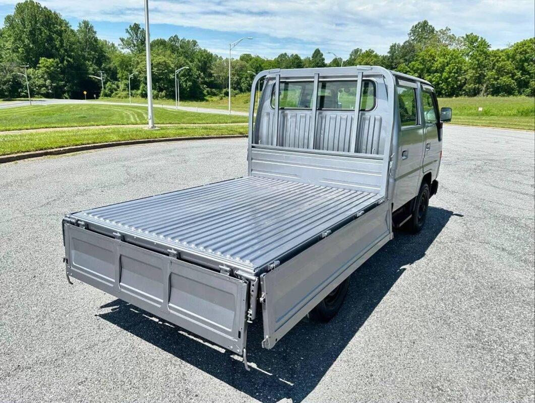 White double cab truck with an open cargo bed viewed from the rear