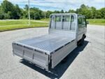 White double cab truck with an open cargo bed viewed from the rear